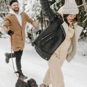 Happy couple walking their dog in a snowy winter forest, enjoying the fun and cold weather.